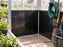 Black HDPE greenhouse wall panels in a corner used for hose reel and garden tool storage
