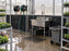 Black greenhouse wall panels installed behind a stainless utility sink and hose reels
