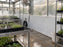 White HDPE greenhouse wall panels near misting irrigation lines over seedling trays
