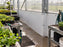 White HDPE greenhouse wall panels behind potting tables with seedling trays
