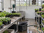 White greenhouse wall panels between a utility sink and exhaust fan with flower trays on both sides
