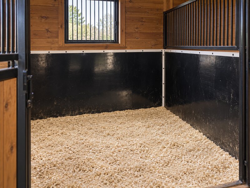 HDPE horse stall wall liner installed around a stall corner with wood upper walls
