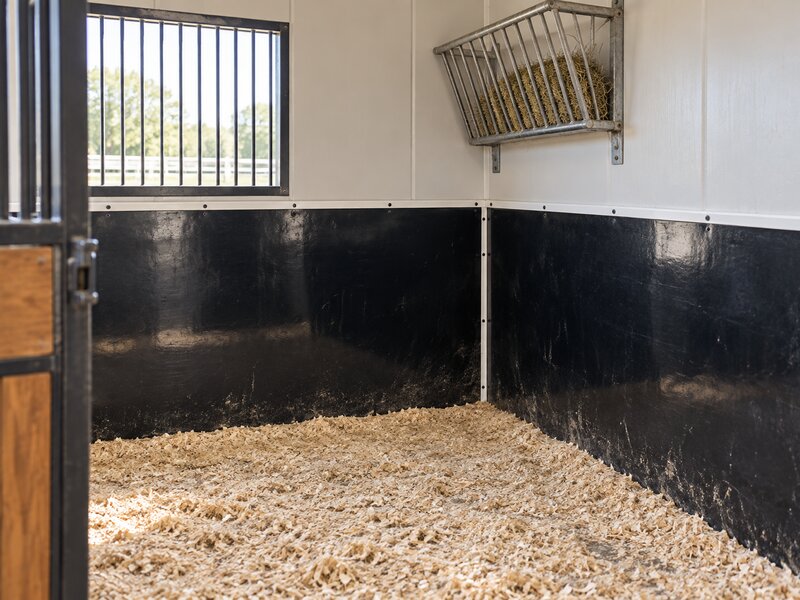 HDPE stall wall liner installed across two adjoining horse stalls with a grain feeder

