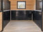 Black stall wall liner installed below a white-paneled stall wall with a hanging hay feeder
