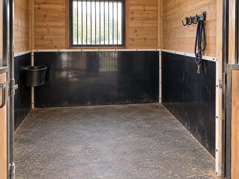 HDPE horse stall wall liner with a water bucket and lead rope hooks mounted above
