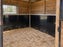 Black stall wall liner installed in a wood-paneled horse stall corner with natural light
