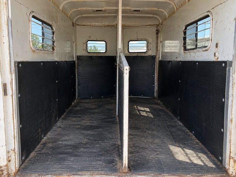 Black wall liner installed in a vintage horse trailer interior with barred windows
